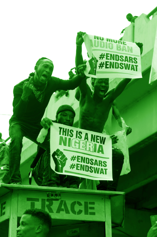 3 men on top of a shop holding protest signs against SARS and SWAT.