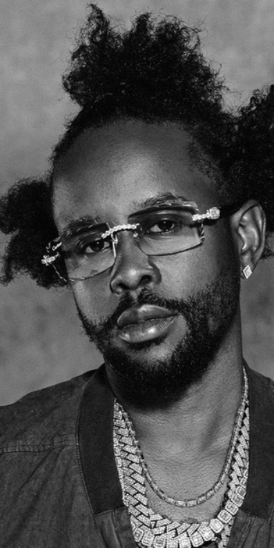 Male artist wearing sunglasses with hair gathered in three sections