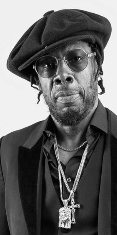 Male artist wearing a hat sunglasses and chains.