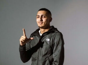 Male artist with his hands up making an L shape.
